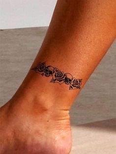 a woman's foot with a tattoo on the side of her leg that has roses and skulls on it