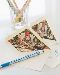 two polaroid pictures sitting on top of an envelope next to a pen and pencil