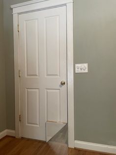 an empty room with a white door and hard wood floors