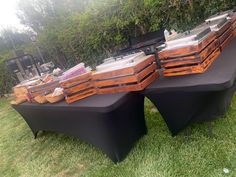 several wooden crates sitting on top of a table covered in black cloths and grass