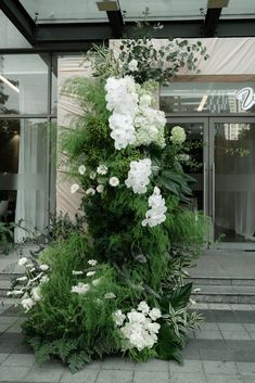 white flowers and greenery are growing on the side of a building's entrance