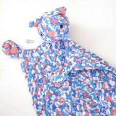 a crocheted teddy bear laying on top of a white table next to a blue and pink blanket