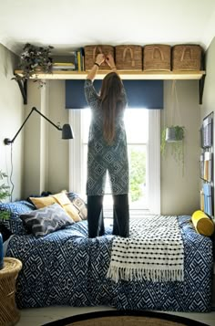 a woman standing on top of a bed next to a window