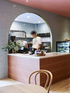 a restaurant counter with a man working behind it and a person sitting at the counter