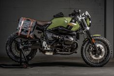 a green and black motorcycle parked next to a gray wall with a brown leather bag on the back