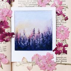 some pink flowers and purple watercolors on an open book with pages in the background