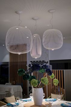 three hanging lights above a table with plates and flowers