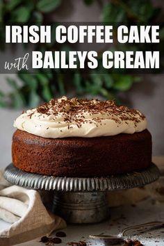 a cake with white frosting and chocolate sprinkles on top sitting on a silver plate