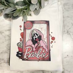 a white t - shirt with an image of a woman eating popcorn and the words barbie on it