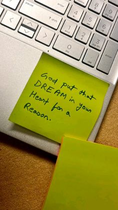 a yellow sticky note sitting on top of a laptop computer next to an open keyboard