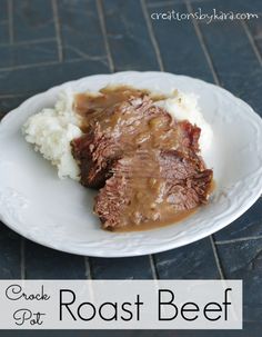 a white plate topped with meat and gravy on top of mashed potatoes