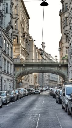 cars are parked on the street in front of tall buildings and an overpass above them