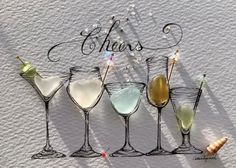 four wine glasses are lined up with the word cheers