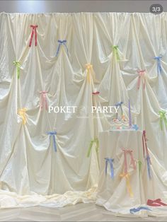 the curtain is decorated with colorful ribbons and bows on it's sides, along with a cake table