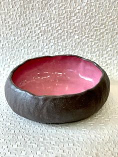 a black and pink bowl sitting on top of a white tablecloth covered wallpaper