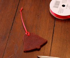 a piece of red string sitting on top of a wooden table next to a pair of scissors