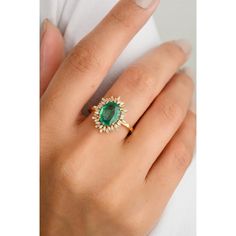 a woman's hand wearing an emerald and diamond ring