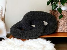 two black donuts sitting on top of a wooden table next to a potted plant