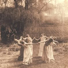 four women in long dresses are holding hands