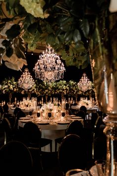 an elegant table set up with chandeliers and greenery in the centerpieces