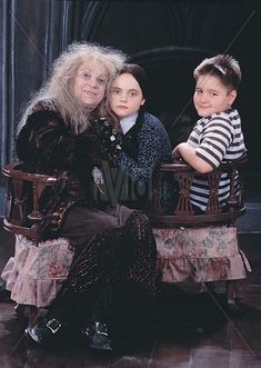 an older woman and two children sitting on a chair