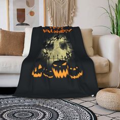 a living room with a couch, chair and rug covered in a halloween themed blanket