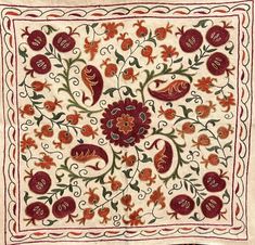 an embroidered square with red flowers and leaves on white fabric, in the middle of a floral