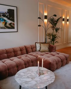 a living room with a couch, table and two candles on the coffee table in front of it