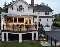 a large white house with stairs leading up to the front door and covered patio area