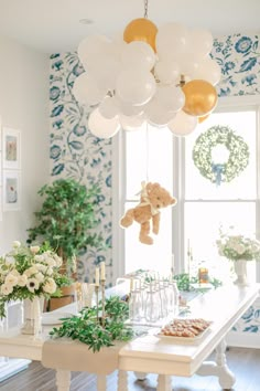 a dining room table with balloons hanging from it's ceiling and flowers in vases on the table