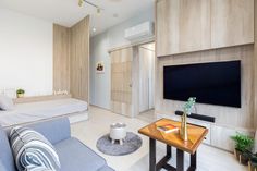 a living room filled with furniture and a flat screen tv mounted on a wall above a wooden table