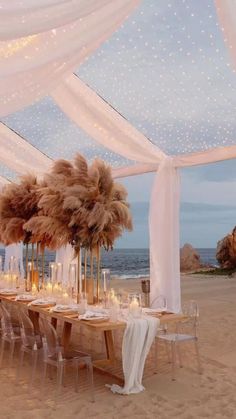 an outdoor wedding setup on the beach with white draping and pamolite centerpieces