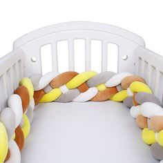 a white crib with a yellow and grey rope on it