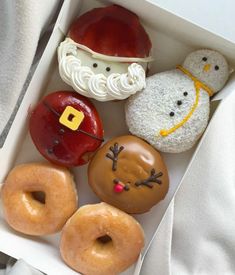 an open box filled with donuts covered in frosting and decorated like santa claus