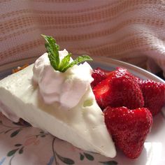 a piece of cheesecake with strawberries and whipped cream on the top is sitting on a plate