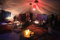 a group of people sitting in a tent with candles