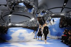 models walk down the runway in front of shiny balls