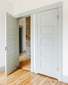 an empty room with two open doors and hard wood flooring on either side of the door