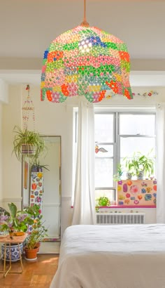 a bedroom with a bed, window and hanging lights in the ceiling is decorated with colorful beads