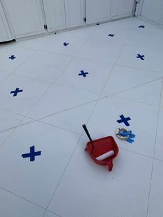 a red wagon with a toothbrush in it sitting on the floor next to blue crosses