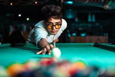 a man in sunglasses is playing pool