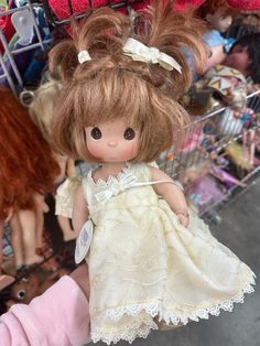 a close up of a doll in a toy shopping cart with other dolls behind it