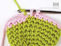 a crocheted pot holder with a pink handle and green yarn on it, next to a pair of scissors