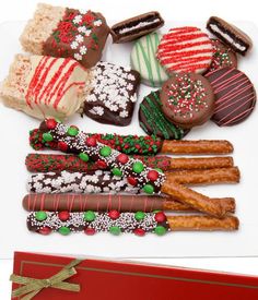 an assortment of decorated cookies and pastries on a white plate next to a red box