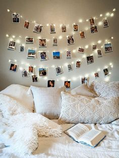 a white bed topped with lots of pillows and pictures hanging on the wall above it