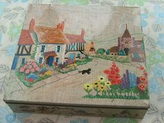 a small box with an image of a village on the front and flowers in the back