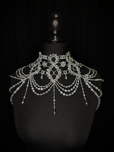 a black mannequin with white beads and chains on it's back neck