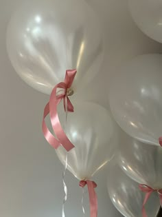 several white balloons with pink ribbons tied to them