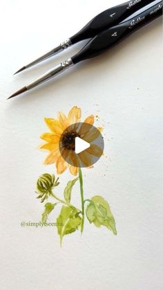 a sunflower painted with watercolors on paper next to a pair of scissors