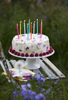 a white cake with many lit candles on it sitting on top of a wooden table